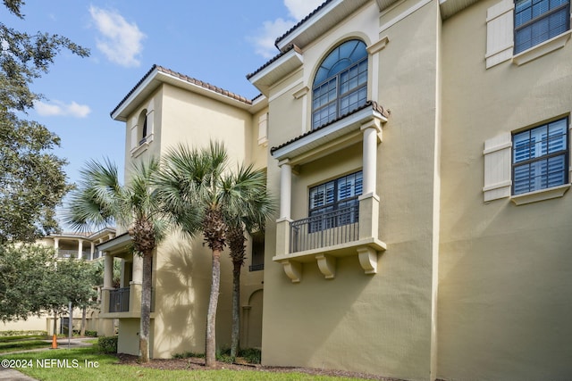 view of side of home with a tile roof and stucco siding