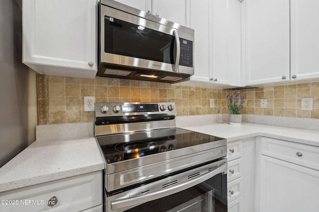 kitchen with stainless steel appliances, tasteful backsplash, light stone countertops, and white cabinets