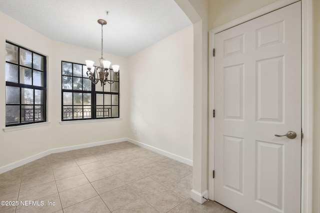 unfurnished dining area with an inviting chandelier, light tile patterned floors, and baseboards