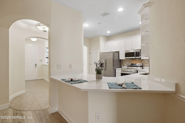 kitchen featuring a peninsula, white cabinetry, visible vents, and appliances with stainless steel finishes