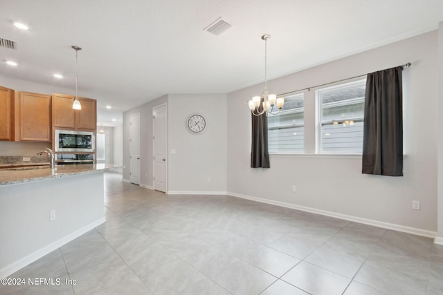 interior space with light stone counters, decorative light fixtures, visible vents, a sink, and built in microwave