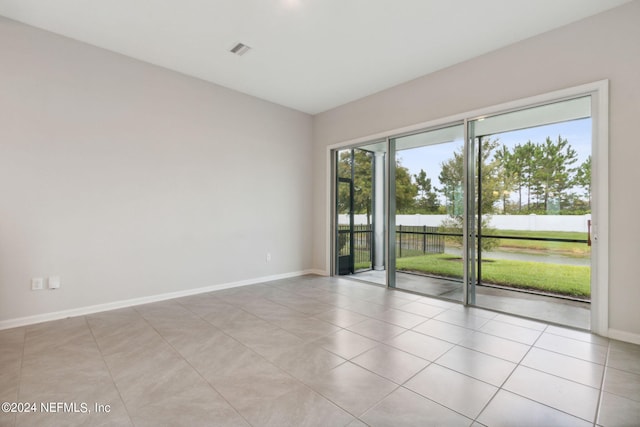 unfurnished room featuring baseboards, visible vents, and light tile patterned flooring