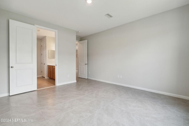 unfurnished bedroom featuring light tile patterned floors, baseboards, visible vents, and connected bathroom