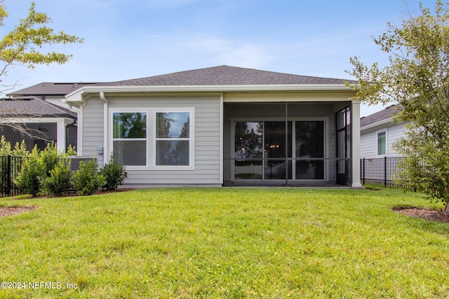 rear view of property featuring a sunroom, roof with shingles, fence, and a yard