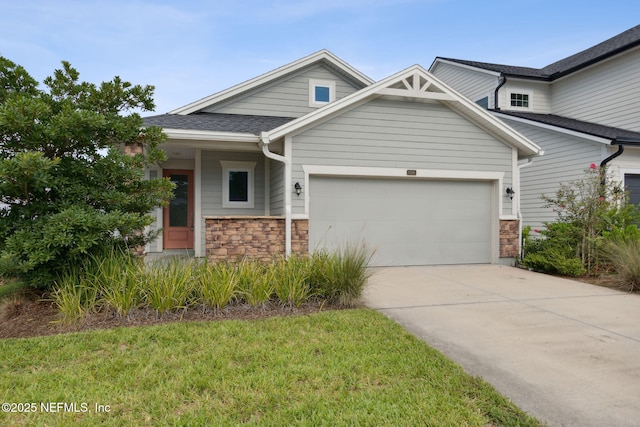 view of front facade with a garage, a shingled roof, concrete driveway, stone siding, and a front lawn