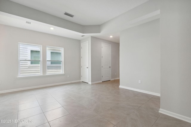 unfurnished room featuring baseboards, visible vents, and recessed lighting