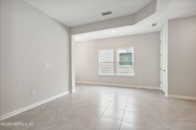 spare room featuring light tile patterned floors, visible vents, and baseboards