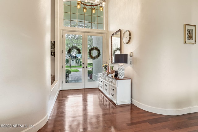 entrance foyer featuring a towering ceiling, an inviting chandelier, french doors, and dark hardwood / wood-style floors