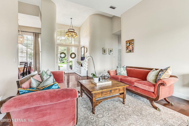 living room with high vaulted ceiling, french doors, hardwood / wood-style floors, and a chandelier