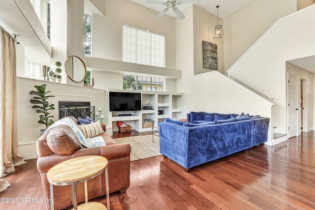 living room featuring ceiling fan, hardwood / wood-style flooring, and a towering ceiling