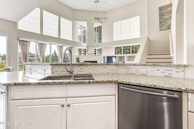 kitchen featuring backsplash, dishwasher, sink, light stone countertops, and ceiling fan