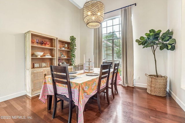 dining area featuring dark hardwood / wood-style flooring, a notable chandelier, and high vaulted ceiling