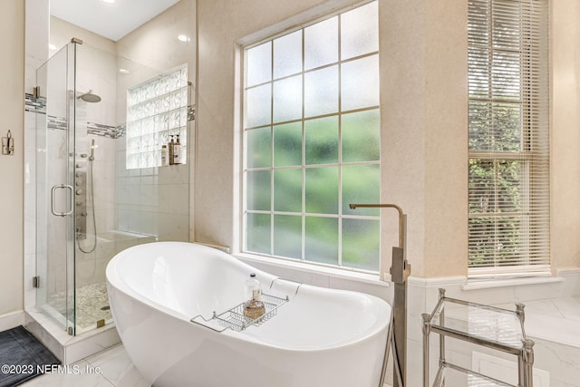 bathroom with a wealth of natural light, tile patterned flooring, and separate shower and tub