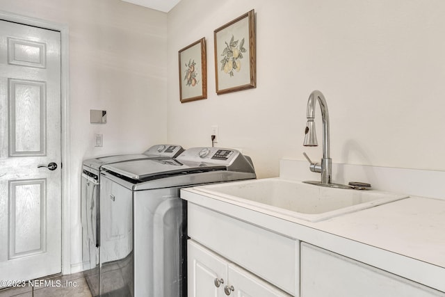 laundry area with independent washer and dryer, light tile patterned floors, sink, and cabinets