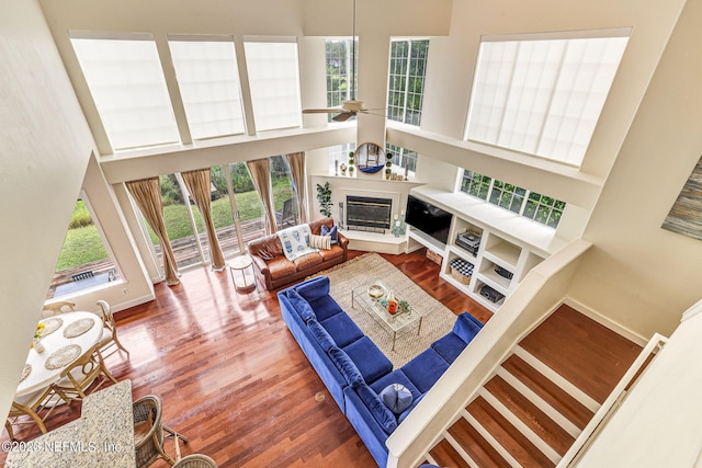 living room with a high ceiling, ceiling fan, and hardwood / wood-style flooring