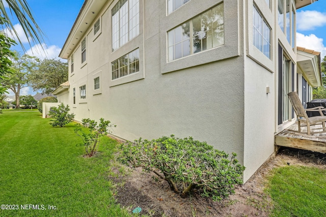 view of side of home with a deck and a lawn