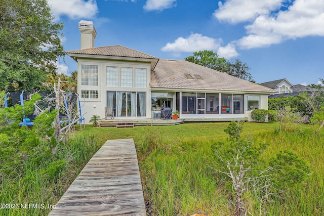 rear view of house with a sunroom and a lawn