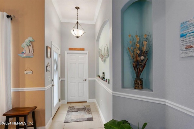 entrance foyer featuring crown molding and light tile patterned floors