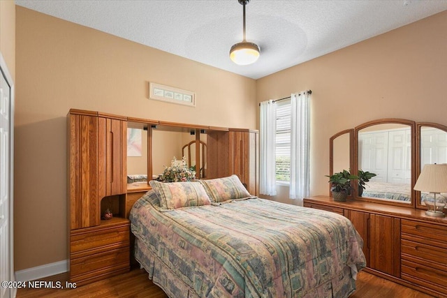 bedroom with a textured ceiling and dark wood-type flooring