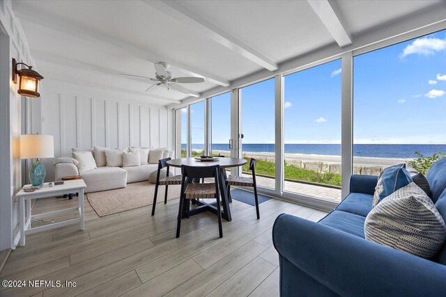 sunroom with a healthy amount of sunlight, beamed ceiling, a beach view, and a water view