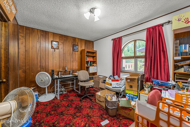 office area with carpet floors, a textured ceiling, and wood walls