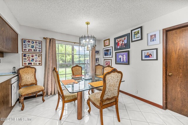 dining area featuring a textured ceiling, a notable chandelier, and light tile patterned flooring