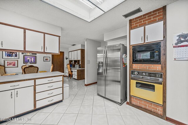 kitchen featuring stainless steel fridge with ice dispenser, black microwave, oven, and white cabinetry