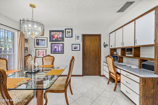 tiled dining space featuring a notable chandelier and a textured ceiling