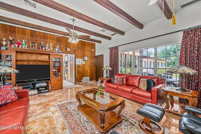 living room featuring ceiling fan, tile patterned flooring, wood walls, beam ceiling, and a textured ceiling