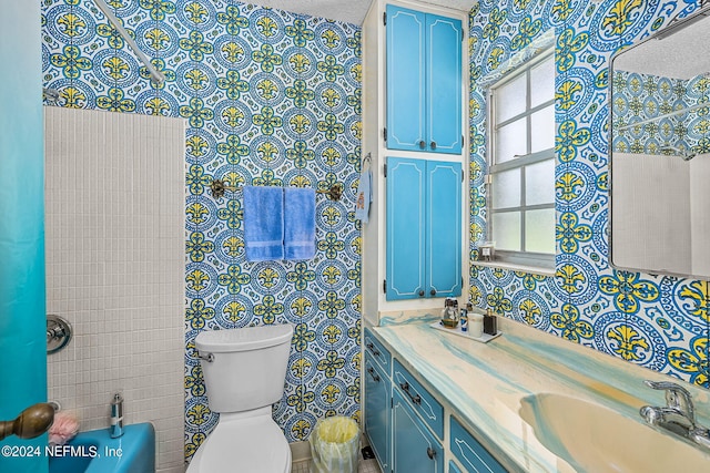 bathroom featuring toilet, a textured ceiling, vanity, and tile walls