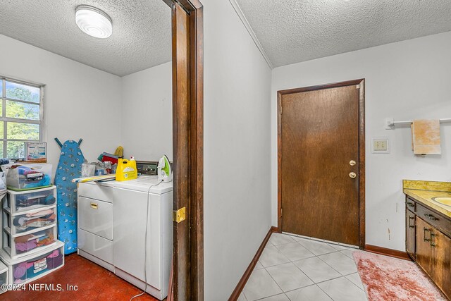 laundry room with washing machine and clothes dryer, a textured ceiling, and light tile patterned floors