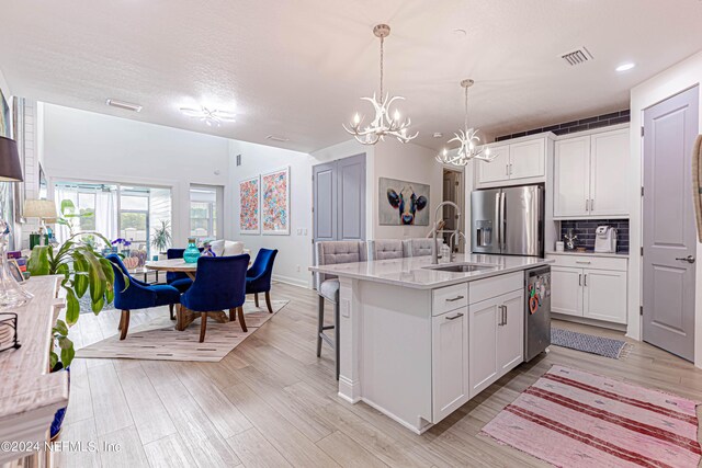 kitchen with a sink, appliances with stainless steel finishes, visible vents, white cabinets, and an inviting chandelier
