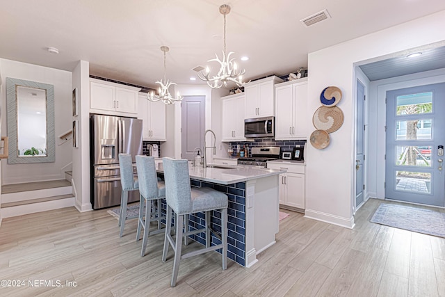 kitchen with stainless steel appliances, a center island with sink, a sink, a breakfast bar area, and an inviting chandelier