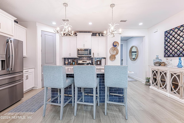 kitchen with visible vents, stainless steel appliances, an inviting chandelier, and tasteful backsplash