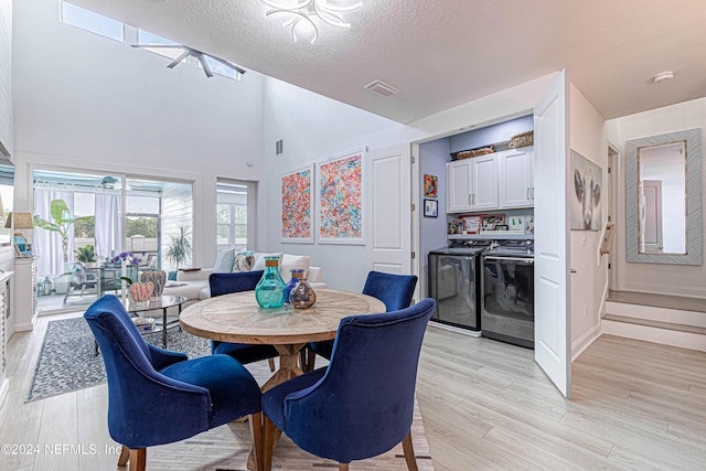 dining area with a textured ceiling, visible vents, independent washer and dryer, a towering ceiling, and light wood-style floors