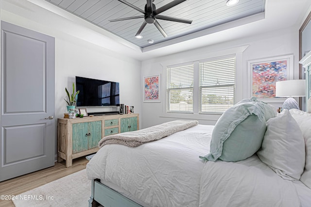 bedroom featuring a ceiling fan, wooden ceiling, a tray ceiling, and light wood-style floors