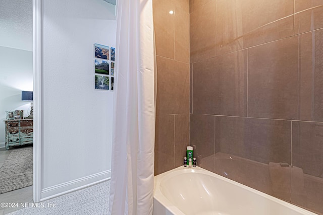 bathroom featuring baseboards, a washtub, and curtained shower