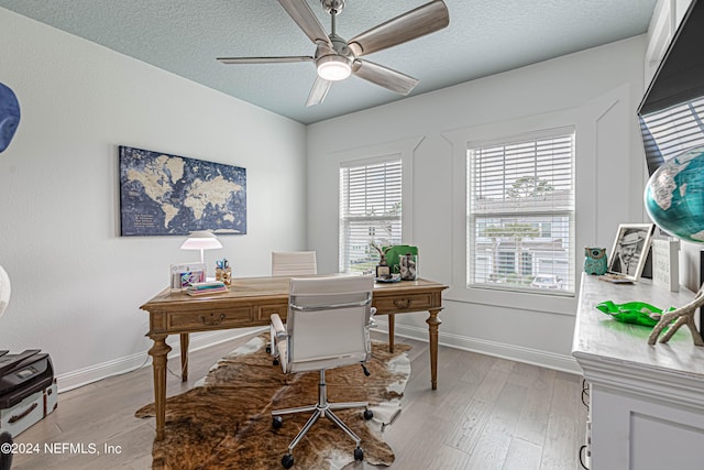 office area featuring baseboards, a textured ceiling, light wood-style floors, and a ceiling fan