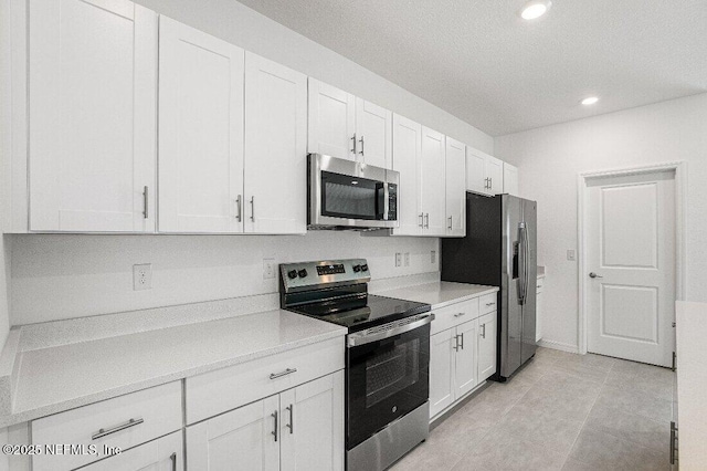 kitchen with light tile patterned flooring, white cabinets, and appliances with stainless steel finishes