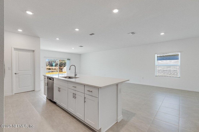 kitchen with light tile patterned flooring, dishwasher, sink, white cabinets, and a kitchen island with sink