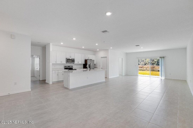 kitchen with white cabinetry, stainless steel appliances, a kitchen island with sink, and light tile patterned floors