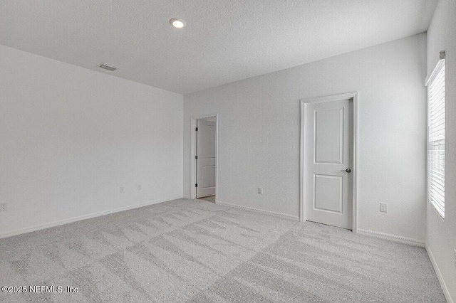 carpeted empty room featuring a textured ceiling