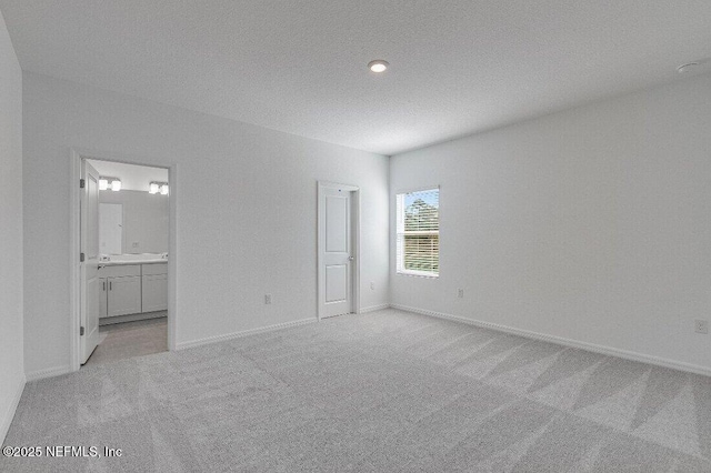 unfurnished bedroom featuring light carpet, connected bathroom, and a textured ceiling