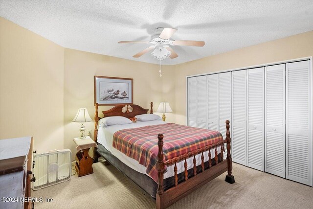 carpeted bedroom with ceiling fan, a closet, and a textured ceiling