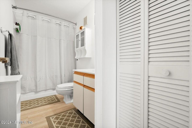 full bath featuring toilet, wood finished floors, vanity, a closet, and shower / bath combo