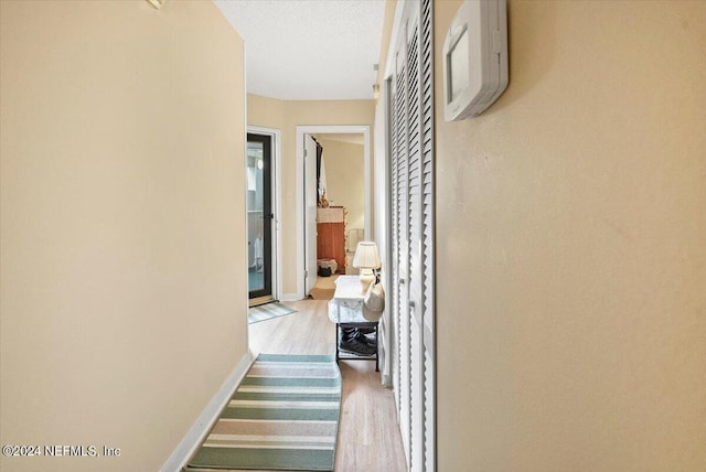 corridor featuring light wood-style flooring and baseboards