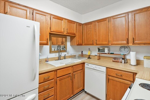 kitchen with sink, white appliances, and light hardwood / wood-style floors