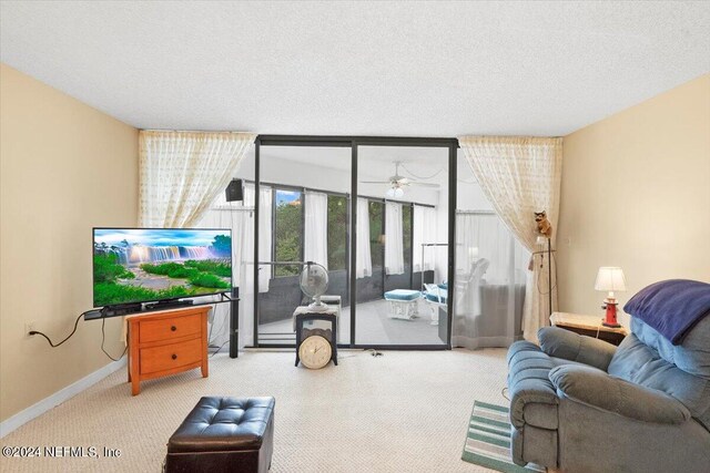 carpeted living room featuring ceiling fan and a textured ceiling