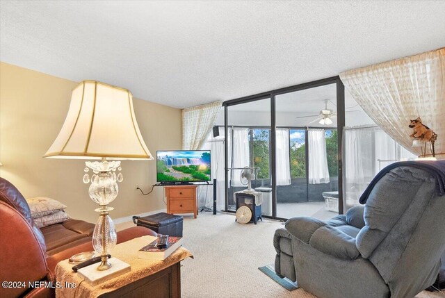 carpeted living room featuring ceiling fan, expansive windows, and a textured ceiling