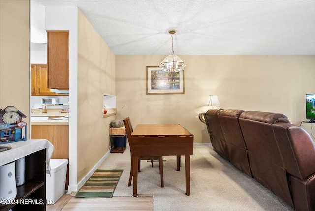 dining room with a chandelier, light carpet, and baseboards